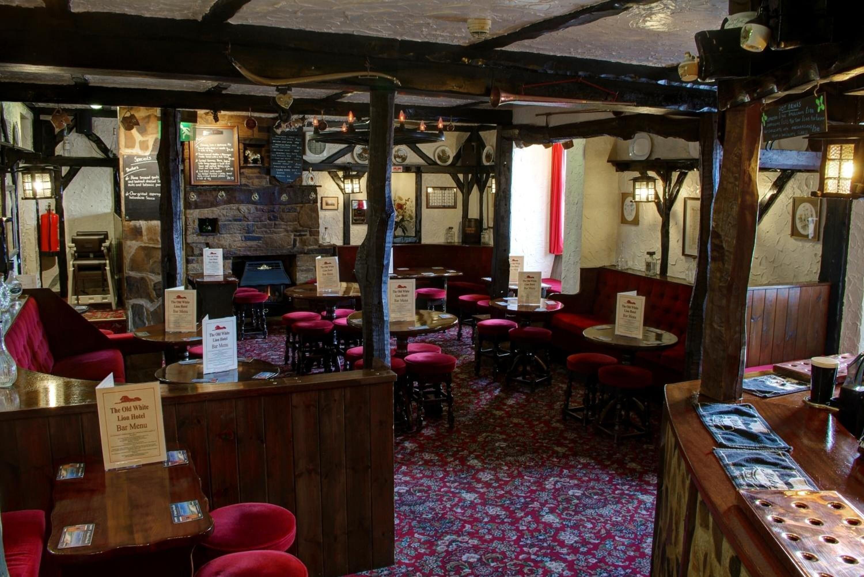 A traditional inn with wooden furniture, stone walls, and a red carpeted floor.