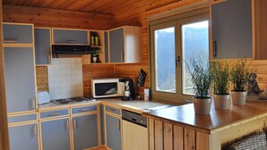 Eine kompakte Küche mit Holzausstattung, einer Mikrowelle, einem Toaster und einem Fenster mit Blick ins Freie.