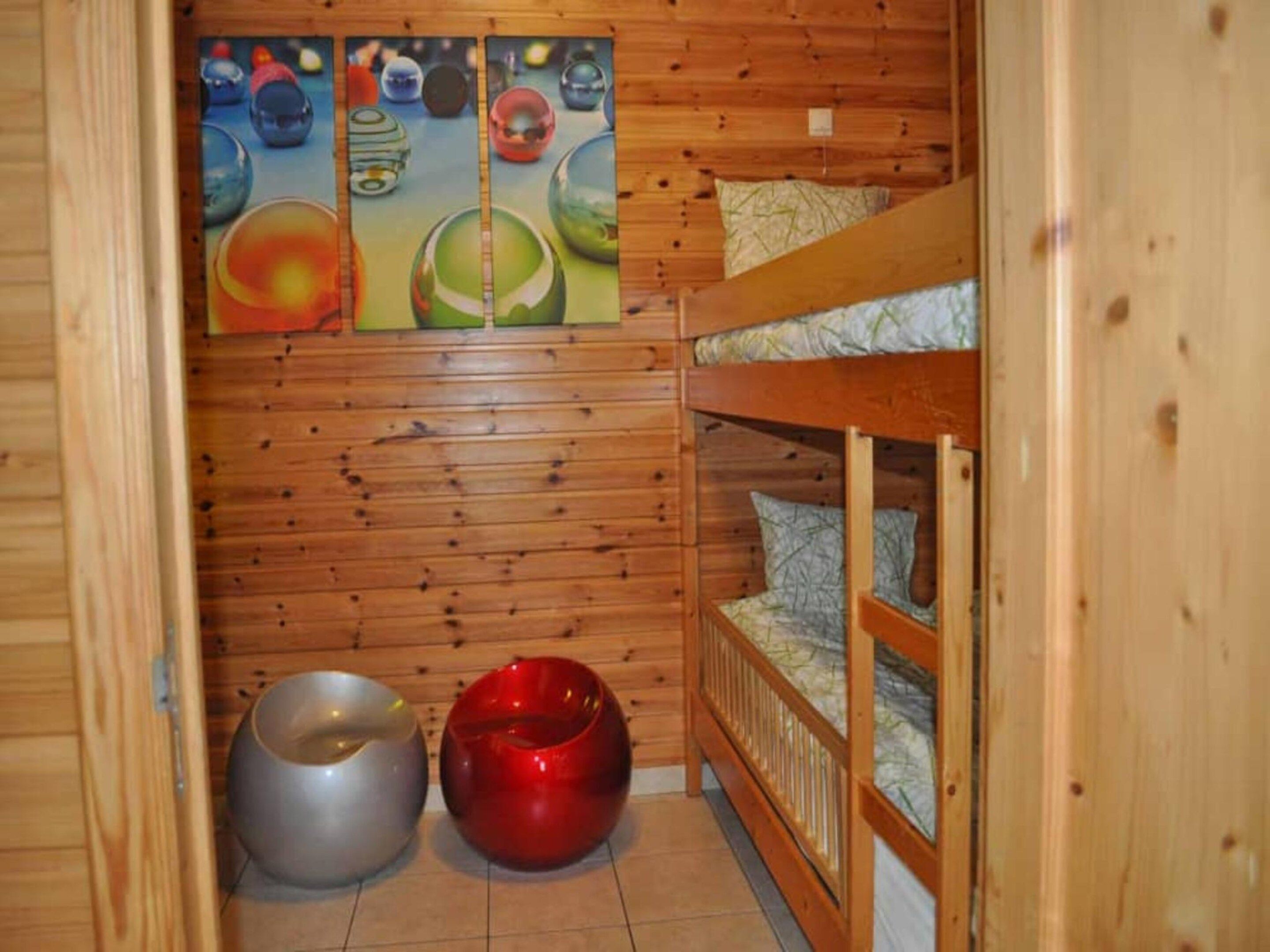 A wooden cabin interior with bunk beds and a painting of colorful bowls.