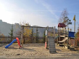 A playground with a slide, climbing structures, and a small shelter.