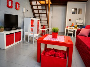 A modern living room with a television, red and white furniture, a plant on a table, and a red sofa. - Holiday Home in Ardennes Near Hotton Caves (La Roche-en-Ardenne)