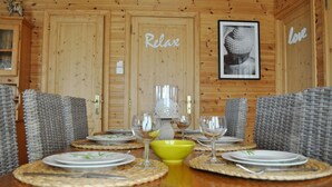 Ein Holzinterieur mit einem Esstisch, gedeckt für vier Personen, umgeben von Korbstühlen.
