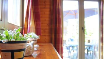 Una mesa de madera con plantas en macetas y vistas a un espacio exterior a través de un ventanal.
