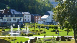 Un parc avec une fontaine, des sculptures en pierre et un étang.