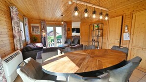 Un intérieur en bois avec une table ronde en bois entourée de chaises, d’un canapé et d’un téléviseur.