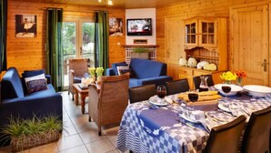 A cozy room with a checkered tablecloth, wicker chairs, and a television on the wall. - Holiday Home in La Roche With Sauna (La Roche-en-Ardenne)
