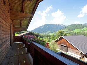 Une cabane en bois dotée d’un balcon donnant sur un paysage montagneux.