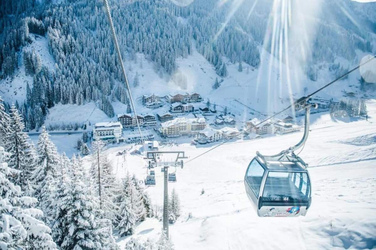 A ski lift with cabins and a snowy mountain landscape in the background.