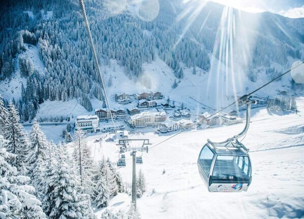 A ski lift with cabins and a snowy mountain landscape in the background.
