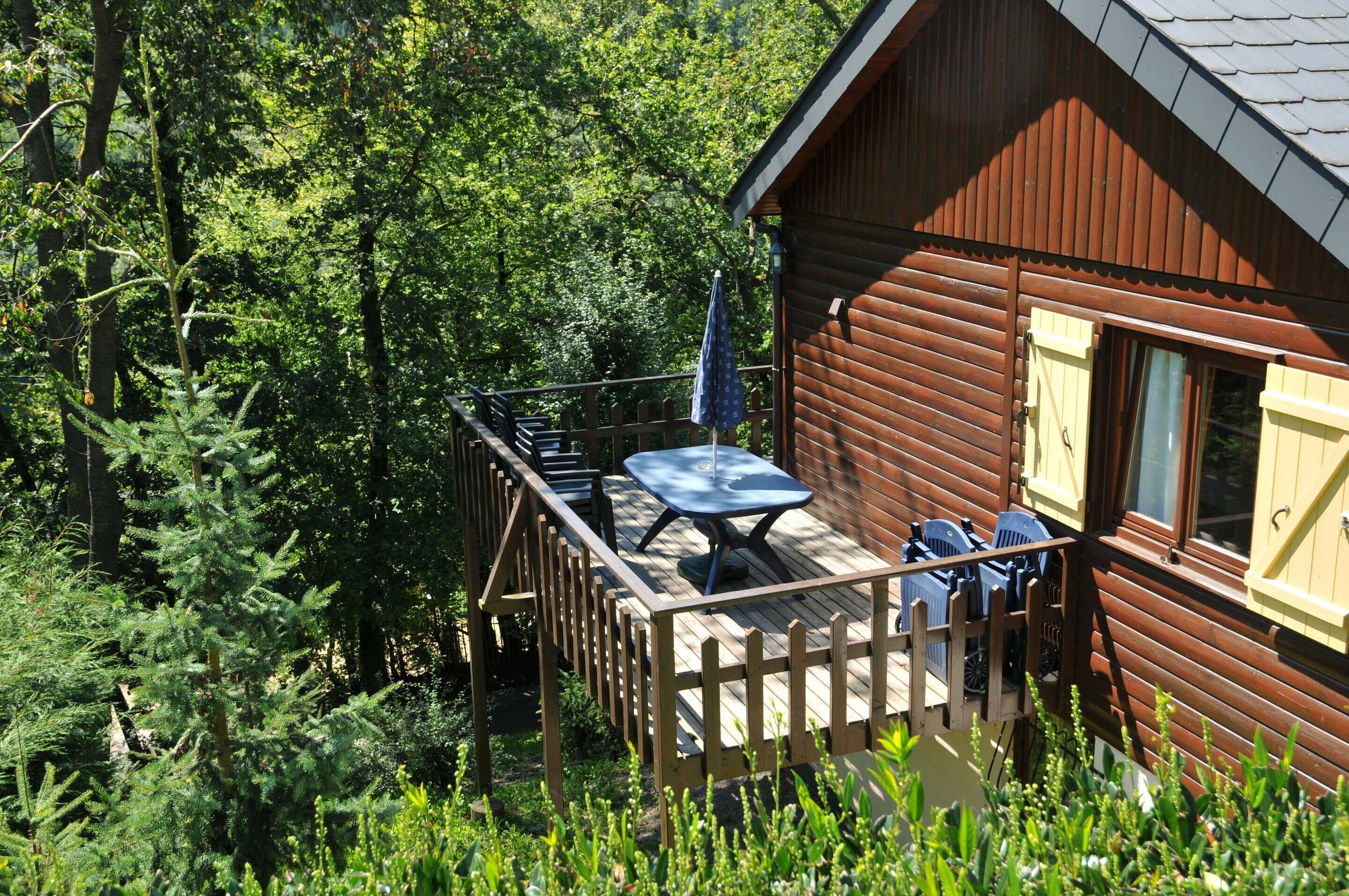 A wooden cabin with a deck, a table, and chairs.