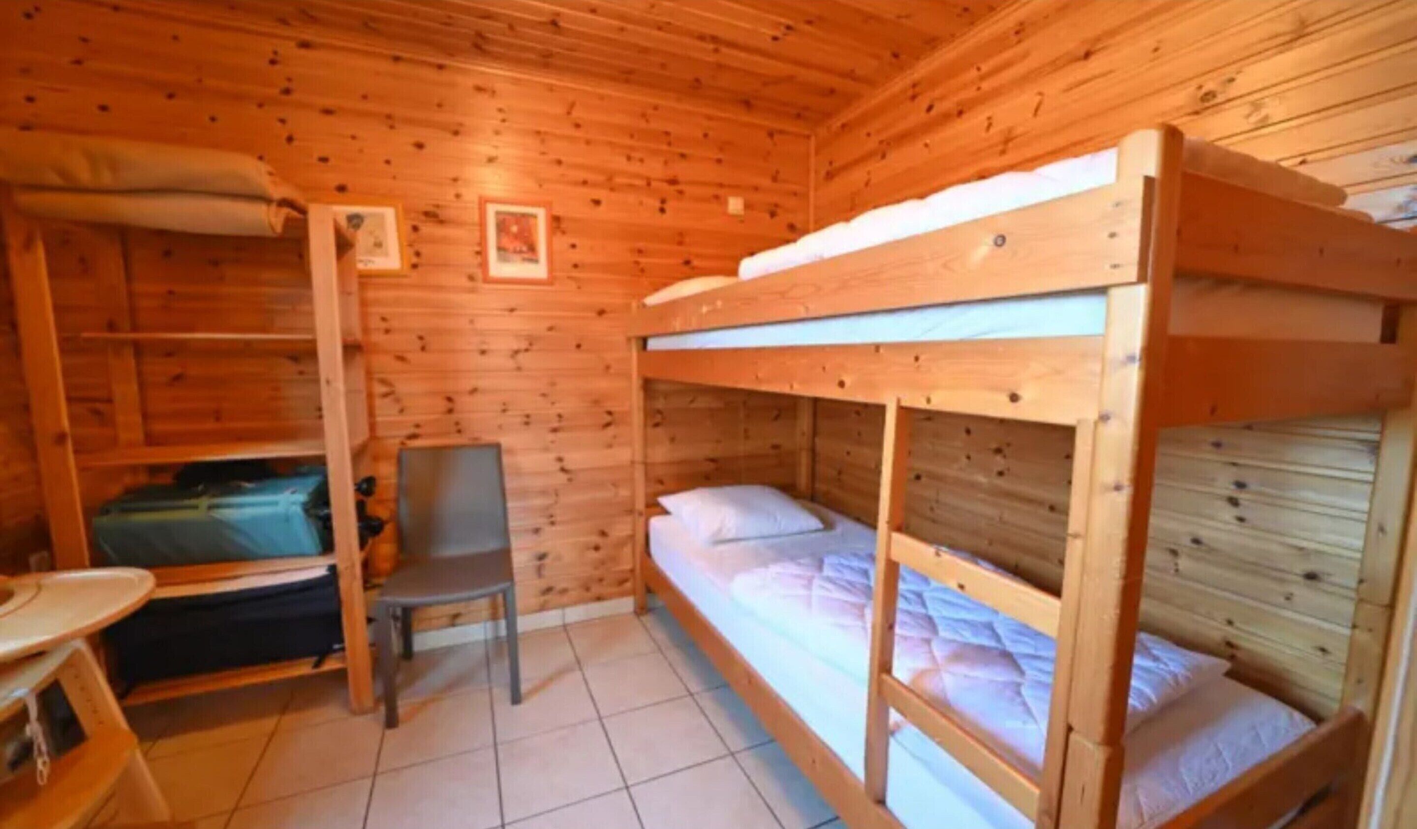 A wooden cabin with bunk beds, a chair, and a small table.