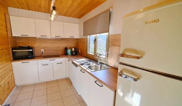 A compact kitchen with white cabinets, a built-in oven, a sink, and a window.