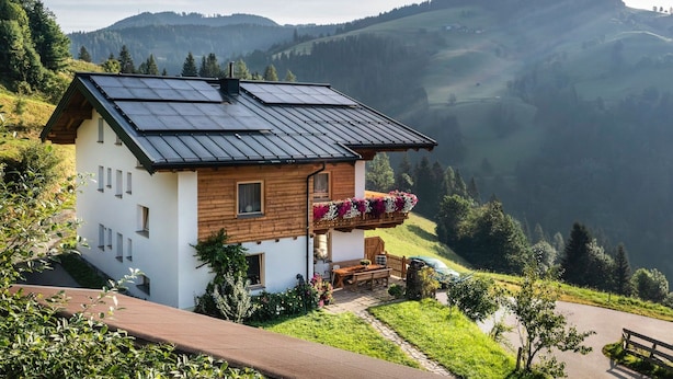 A chalet with a sloped roof, solar panels, and a balcony with flowers. - Cozy Apartment in Sankt Johann im Pongau near Ski Area (Sankt Johann im Pongau)