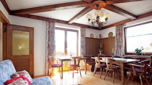 A cozy living room with a wooden ceiling, a dining area with wooden chairs and a table, and a sofa with a patterned blanket. - Cozy Apartment in Sankt Johann im Pongau near Ski Area (Sankt Johann im Pongau)