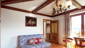 A cozy room with a wooden ceiling, a sofa with patterned cushions, a dining table with chairs, and a painting on the wall. - Cozy Apartment in Sankt Johann im Pongau near Ski Area (Sankt Johann im Pongau)
