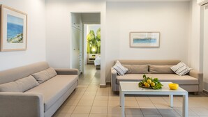A modern living room with two sofas, a coffee table with fruit, and artwork on the walls.