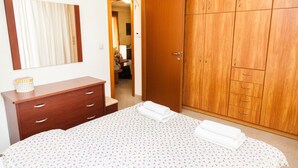 Un dormitorio con cama, un armario de madera, un tocador y un espejo.