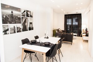 A modern dining area with a white table set for four, black chairs, and a black table runner. - Modern Glamorous Apt in Athens DT (Athens)