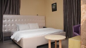 Una camera da letto con un letto grande, un comodino, un tavolino rotondo e una sedia.