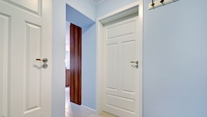 Passadís amb portes blanques, parets de blau clar i un sòl de rajola.