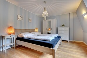 Quarto com cama, luminárias de cabeceira, guarda-roupa e luminária no teto.