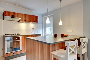 Uma cozinha moderna com armários de madeira, eletrodomésticos de aço inoxidável e uma ilha central com assentos.