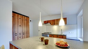 Una cuina moderna amb armaris de fusta, taulell de granat i dues làmpades penjants.