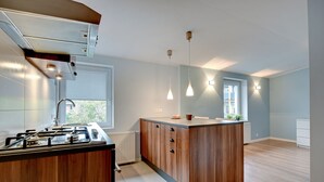 Una cuina moderna amb una illa central, armaris integrats i il·luminació penjant.