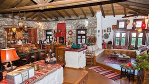 Un intérieur rustique avec des murs en pierre, des poutres en bois, une cheminée et un coin salon confortable.