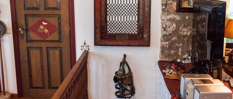 A staircase with a wooden handrail leading to a landing with a patterned rug, a basket, and a wall-mounted decorative item.