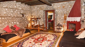 Une chambre traditionnelle avec des murs en pierre, un lit en bois, un grand tapis à motifs et une cheminée.