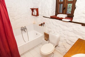 A bathroom with a bathtub, toilet, and a window with a view of greenery. - Picturesque Villa in Parnassos (Delphi)