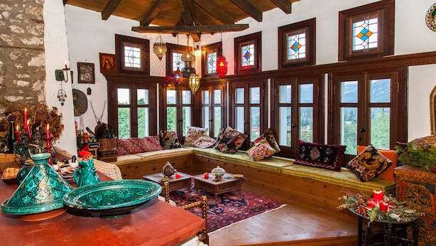 Un intérieur chaleureux avec un banc en bois, de grandes fenêtres et des objets décoratifs.