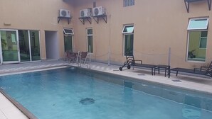 Une piscine avec des chaises longues et un espace salon abrité.