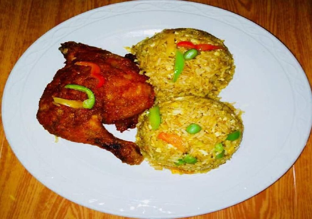 A plate with fried chicken and two portions of fried rice.