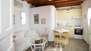 A compact kitchen with a dining area, a white sofa, and a wooden ceiling. - Villa Anemoessa Olive Green with Pool (Mykonos)