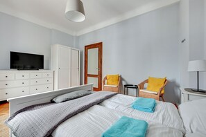 A bedroom with a bed, a television, a wardrobe, a chair, and a lamp.