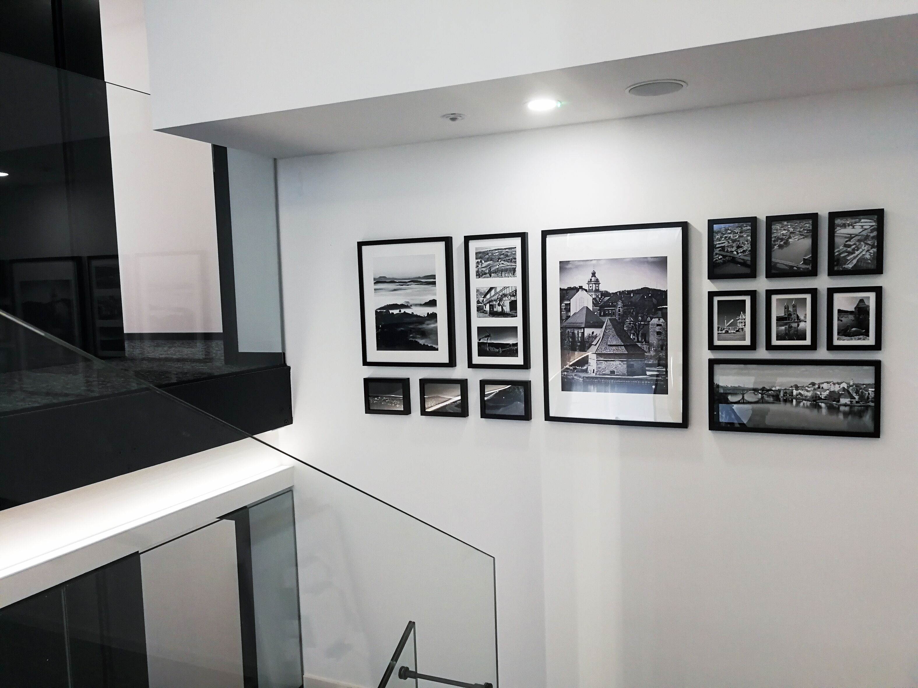 A modern interior with a staircase and a wall displaying framed black and white photographs.