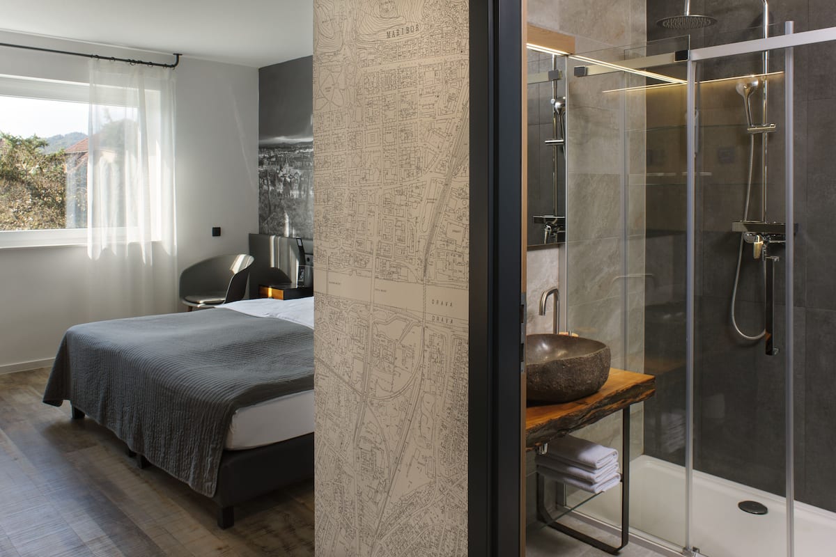 A modern bedroom with a large bed, a map wall, and a shower area with a stone sink.