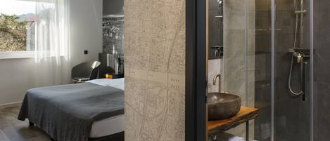 A modern bedroom with a large bed, a map wall, and a shower area with a stone sink.