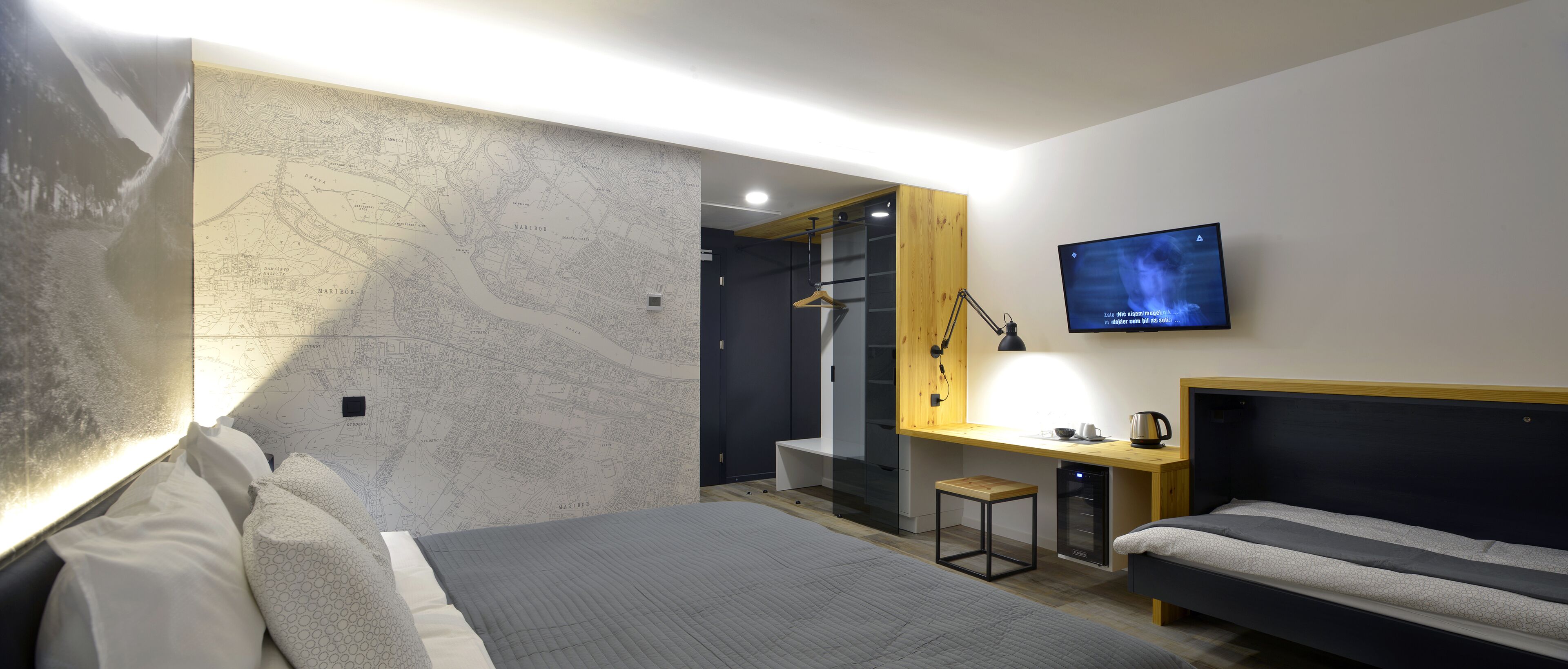 Une chambre d’hôtel moderne avec un grand lit, un bureau équipé d’un ordinateur, une télévision et une armoire.