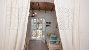 A room with a white sofa, a blue pillow, and a patterned curtain. - Villa Anemoessa Sky Blue with Pool (Mykonos)