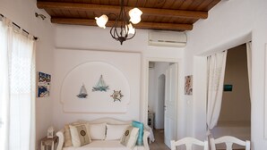 A cozy room with a white sofa, a wooden table, and a ceiling fan. - Villa Anemoessa Sky Blue with Pool (Mykonos)
