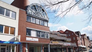 Un immeuble d’appartements situé en ville, doté d’un design moderne et d’une grande fenêtre en arc de cercle au deuxième étage.