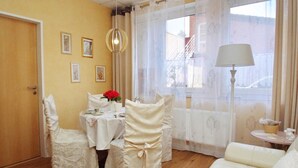 Une pièce comprenant une table à manger dressée pour deux personnes, un canapé et une lampe.