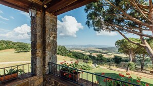 Un balcon en pierre offrant une vue sur un paysage rural, avec des champs et des arbres.