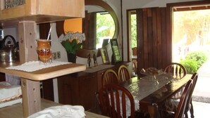 A dining area with a wooden table and chairs, a vase with flowers, and a view of greenery outside. - Beautiful comfortable house (São Sebastião)