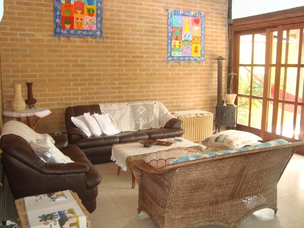 A cozy living room with a brown leather sofa, a wicker chair, and a small table with a vase.