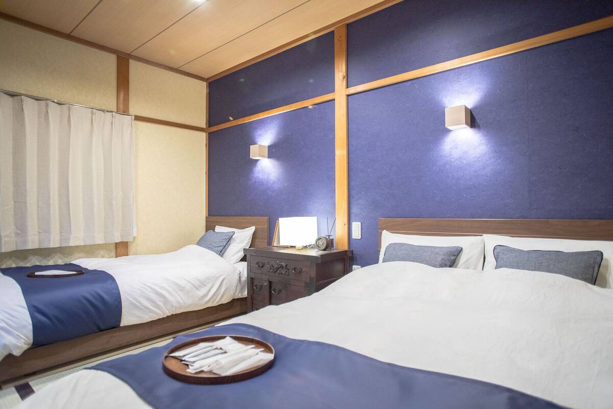 A hotel room with two beds, a wooden headboard, a nightstand, and a window with curtains.