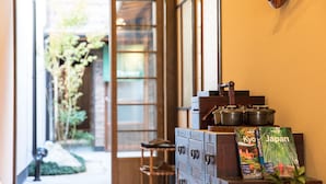A traditional Japanese interior with a wooden cabinet displaying travel books and a small shelf with a teapot. - Nijojo Taiken Inn (Kyoto)